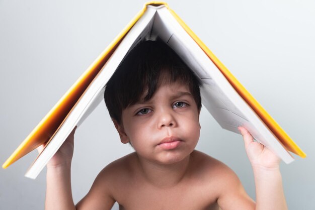 Menino com livro amarelo na cabeça