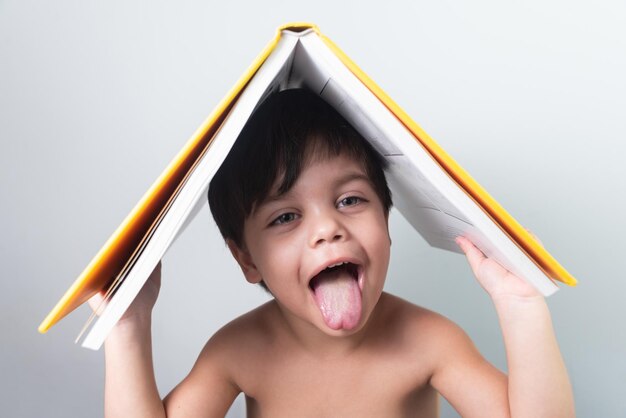 Menino com livro amarelo na cabeça