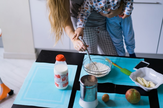 menino com mãe cozinhando na torta da cozinha