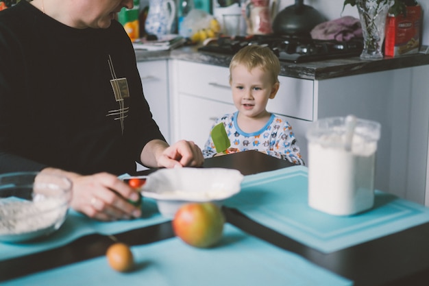 menino com mãe cozinhando na torta da cozinha