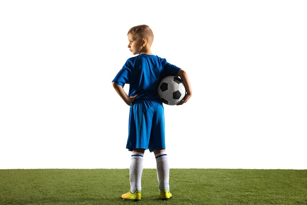 Foto grátis menino como um jogador de futebol ou futebol americano em sportswear em pé com a bola como um vencedor, o melhor atacante ou goleiro na parede branca. ajuste o menino brincando em ação, movimento, movimento no jogo.