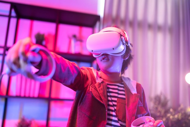 Foto grátis menino criança asiática usa óculos de realidade virtual ou vr headsets em pé e jogando videogame na sala de estar em frente à tv em casa no período de quarentena tecnologia e conceito de inovação luz neon