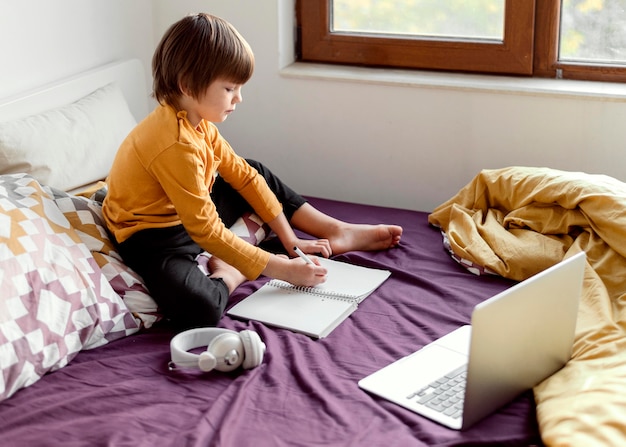 Menino da escola sentado na cama escola virtual