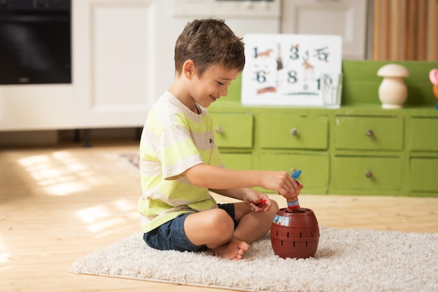 Menino de 7 anos senta no tapete e brinca com brinquedos em casa jogos educativos