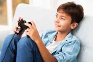 Foto grátis menino de alto ângulo, jogando em casa com joystick