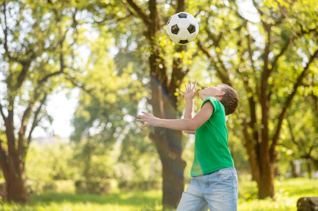 Menino de lado para a câmera jogando bola