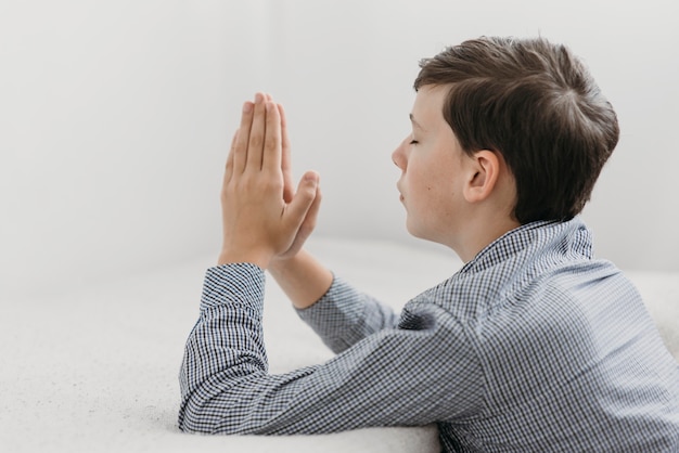 Foto grátis menino de lado rezando pacificamente