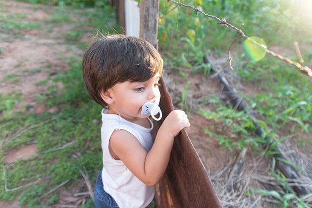 Menino de olhos azuis brincando no quintal