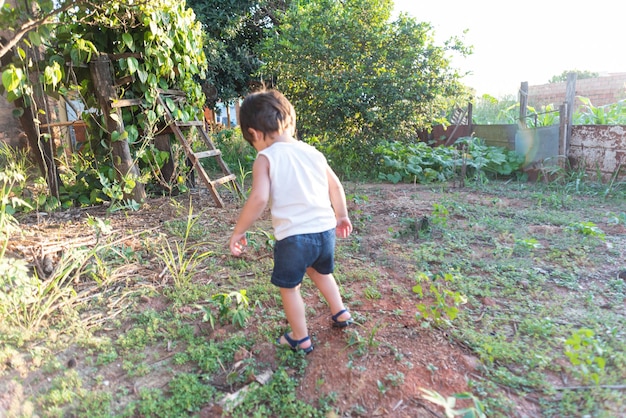 Menino de olhos azuis brincando no quintal