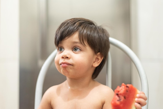 Menino de olhos azuis comendo melancia