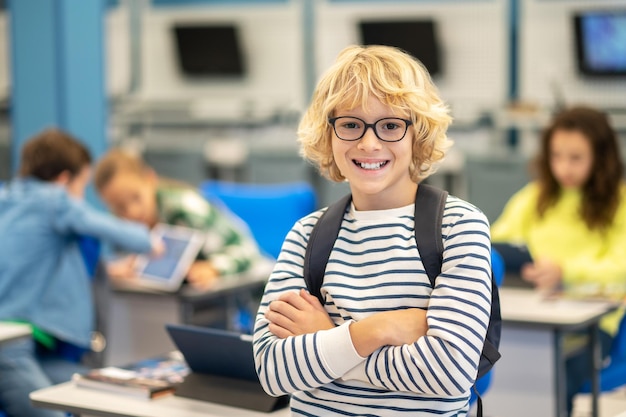 Menino de pé na aula olhando para a câmera