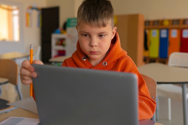 Foto grátis menino de tiro médio aprendendo com laptop