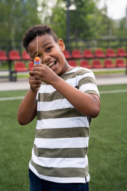 Foto grátis menino de tiro médio brincando com pistola d'água