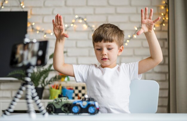 Menino de tiro médio gravando com carros