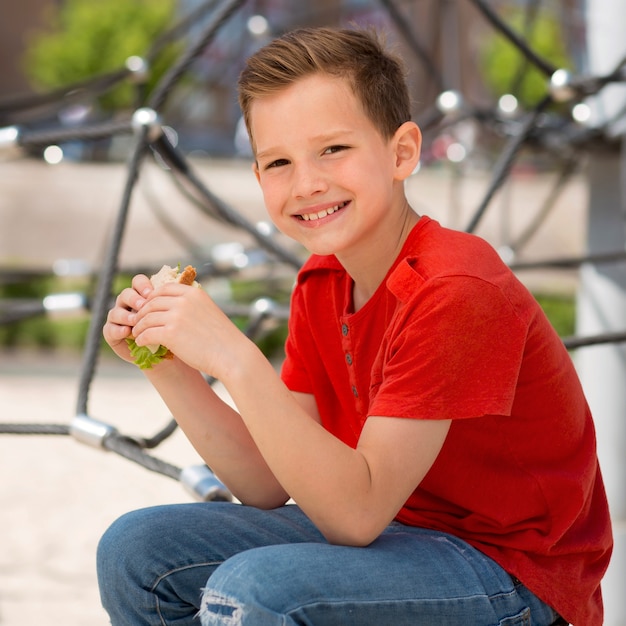 Foto grátis menino de tiro médio segurando sanduíche