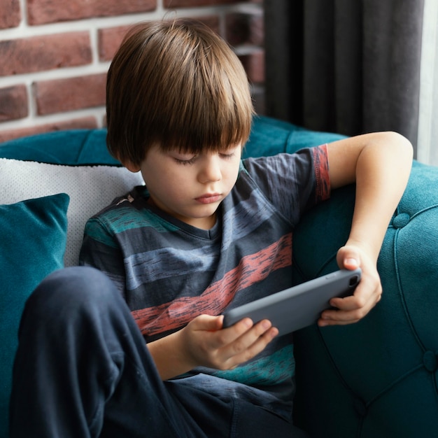 Menino de tiro médio segurando um smartphone