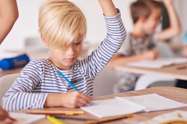 Menino desenhando e levantando a mão