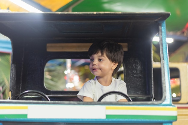 Menino dirigindo caminhão de brinquedo no parque de diversões