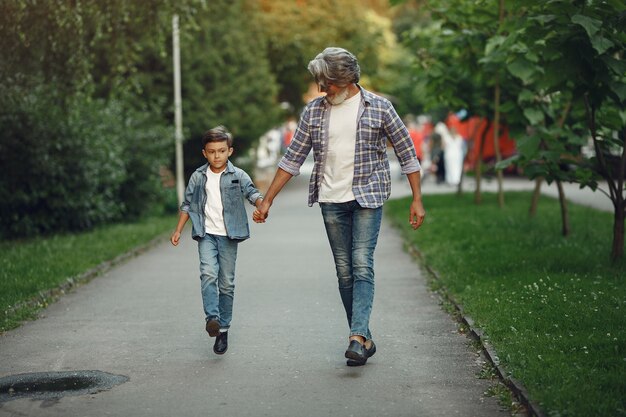 Menino e avô estão caminhando no parque. Velho brincando com o neto.