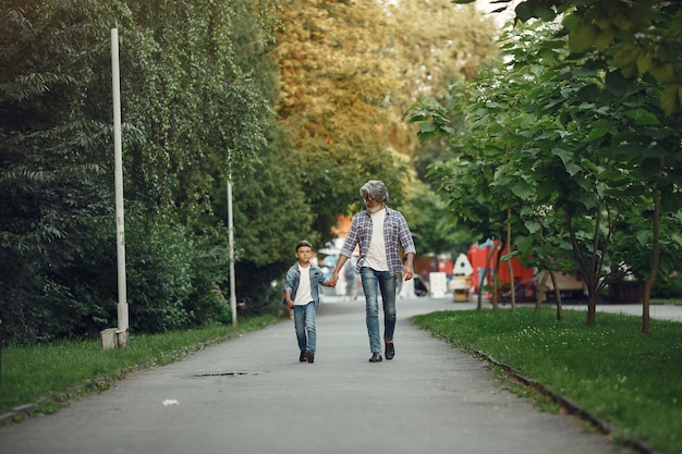 Menino e avô estão caminhando no parque. Velho brincando com o neto.