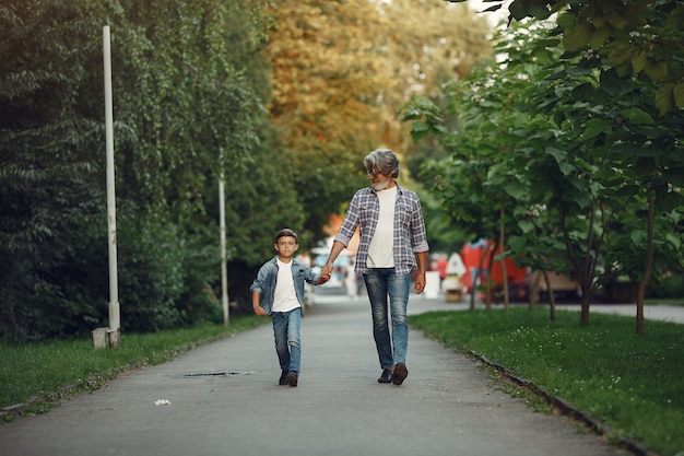 Menino e avô estão caminhando no parque. Velho brincando com o neto.