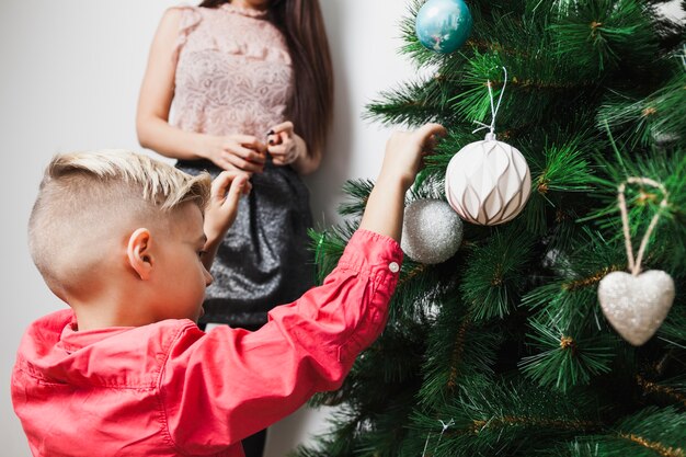 Menino e mãe que decoram a árvore de natal