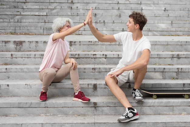 Foto grátis menino e menina batendo os pés enquanto estão sentados na escada