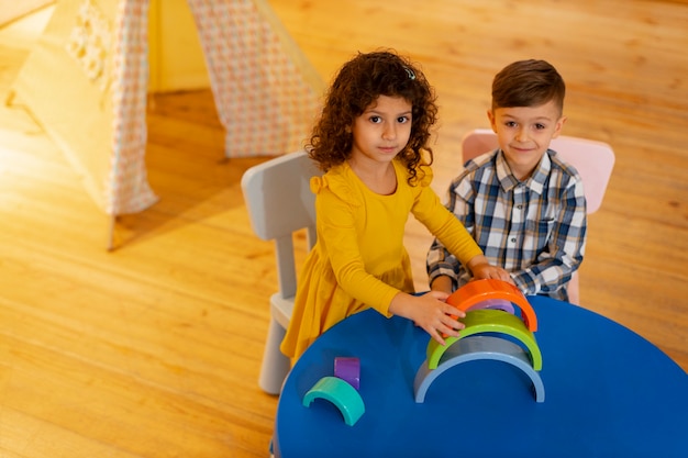 Menino e menina brincando dentro de casa com brinquedos ecológicos