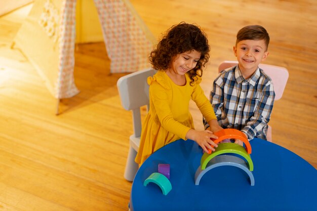 Menino e menina brincando dentro de casa com brinquedos ecológicos