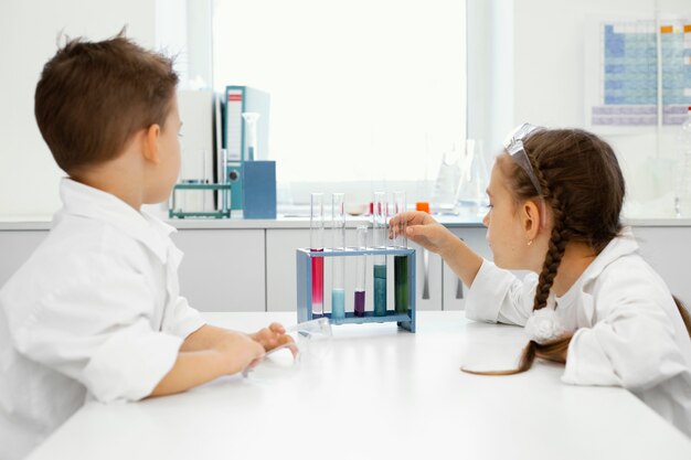 Menino e menina cientistas no laboratório com óculos de segurança