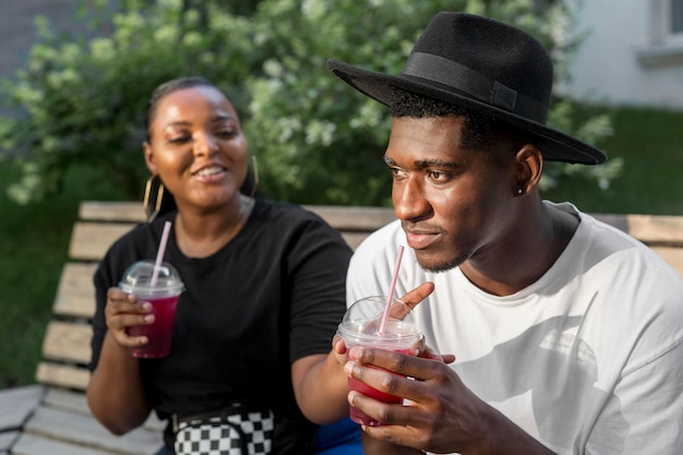 Menino e menina curtindo smoothies lá fora