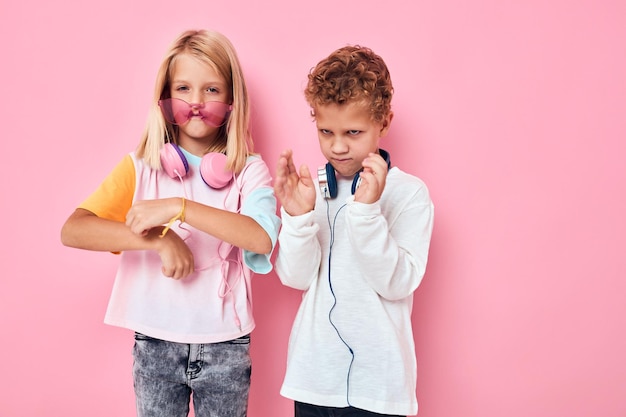 Menino e menina engraçados usando fones de ouvido, posando de plano de fundo cor-de-rosa