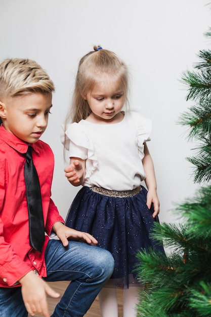 Menino e menina que decoram a árvore de Natal