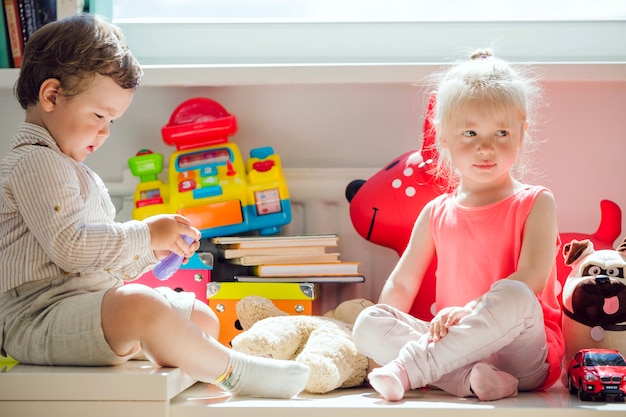 Foto grátis menino e menina sentados na janela posando