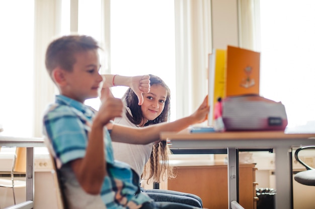 Menino e menina sentados na mesa da escola