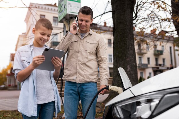 Menino e pai perto de um carro elétrico