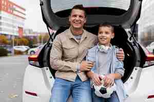 Foto grátis menino e pai perto de um carro elétrico