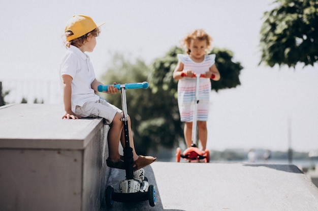 Foto grátis menino e uma menina andando de scooter juntos no parque