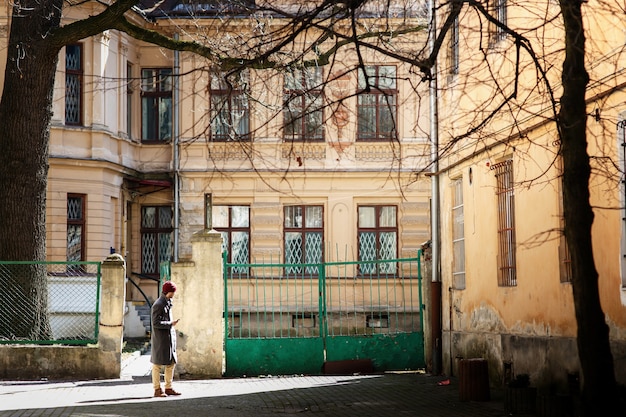 Menino em casaco cinza e chapéu vermelho está na rua