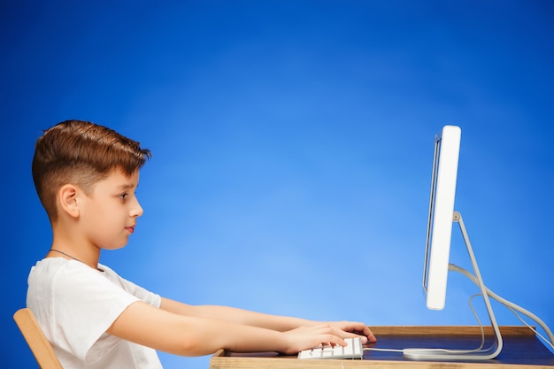 Foto grátis menino em idade escolar, sentado na frente do laptop monitor