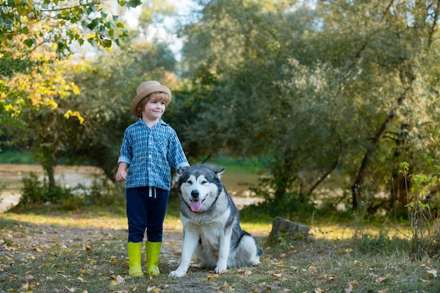 Menino engraçado crianças com cachorro caminhar juntos no conceito de crianças de férias e aventura de campo verde ch ...
