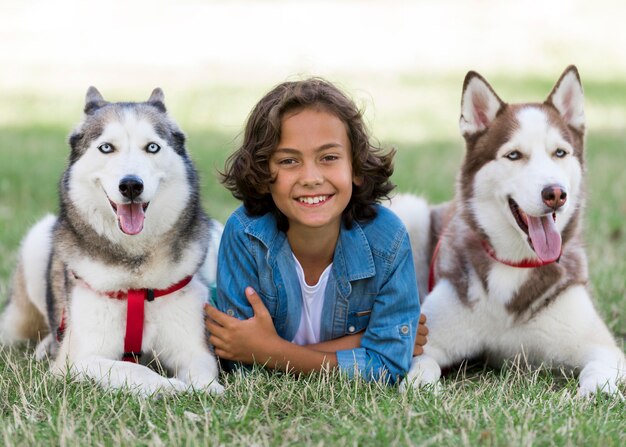 Menino feliz posando com seus cachorros no parque