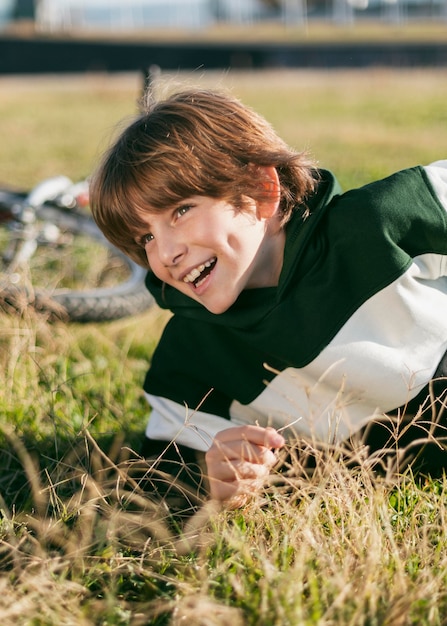 Menino feliz relaxando na grama enquanto andava de bicicleta