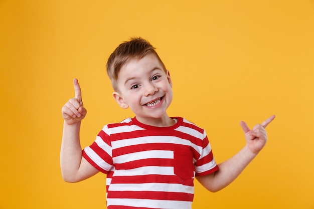 Menino feliz sorridente, apontando os dedos para cima na copyspace