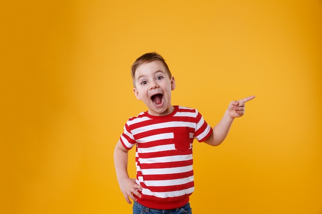 Menino feliz surpreso, apontando os dedos para cima