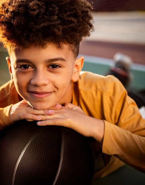 Foto grátis menino fofo posando com uma bola de basquete