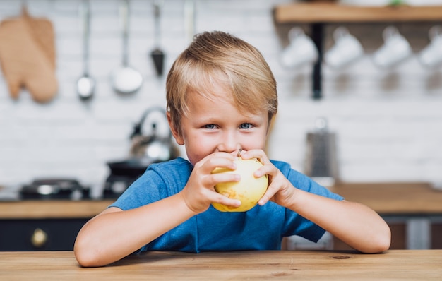 Menino loiro comendo uma maçã