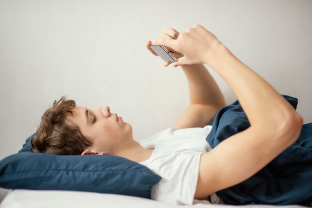 Menino na cama com celular