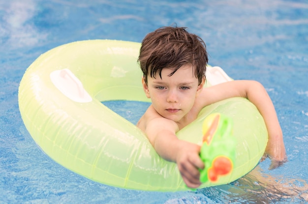 Menino na piscina com bóia