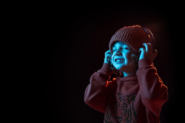 Menino ouvindo música em fones de ouvido com os olhos fechados